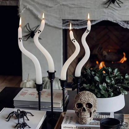 Decorative candles with ghost shapes, skull, and spider decorations on a table in front of a fireplace.