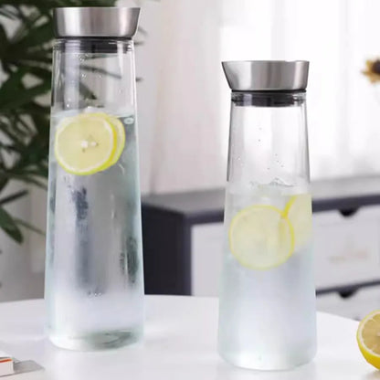 Two glass carafes with metal lids, both filled with water and lemon slices.