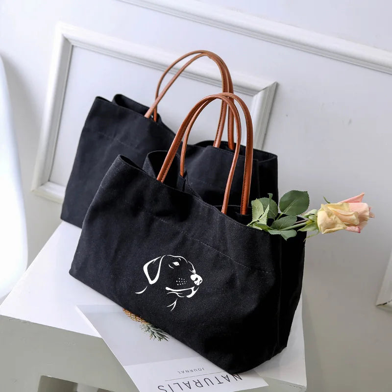 Two black canvas tote bags, one with a dog graphic.