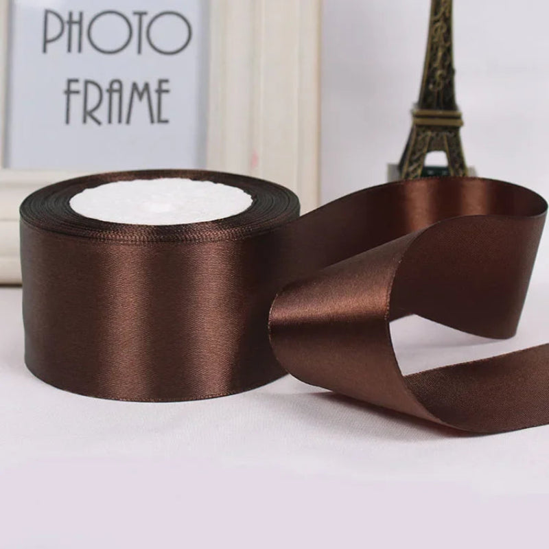 Brown satin ribbon with a spool on a light background