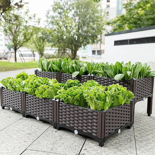 A set of raised, brown, woven plastic garden beds filled with fresh green lettuce and other leafy vegetables.