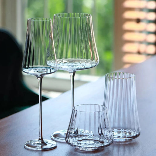 A set of four clear, fluted glasses of varying sizes on a table.