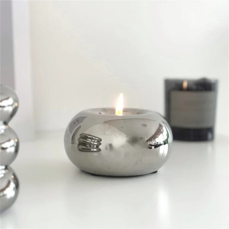 Silver candle holder with a lit candle on a white surface