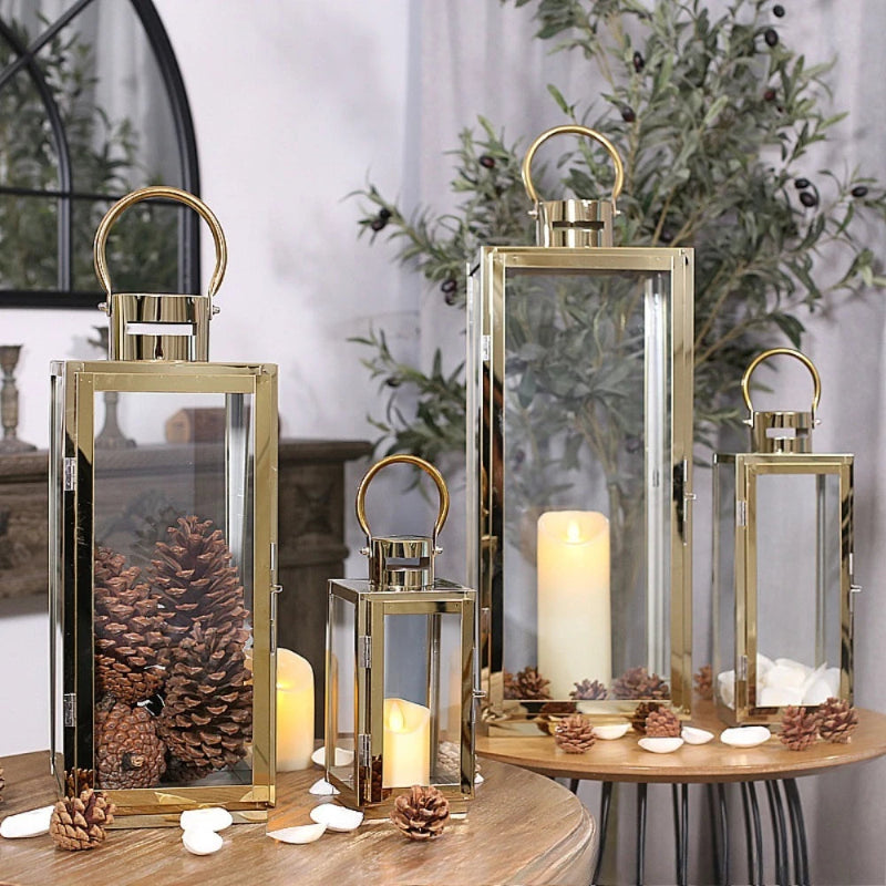 Decorative lanterns with candles and pinecones on a table.