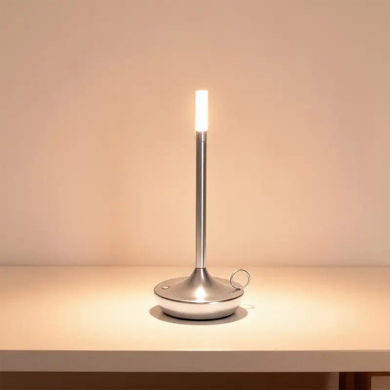 A slender silver LED desk lamp is on, casting a warm light.