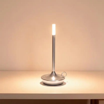 A slender silver LED desk lamp is on, casting a warm light.