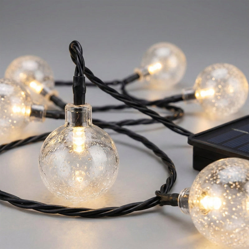 String of clear globe lights with solar panel on a neutral background