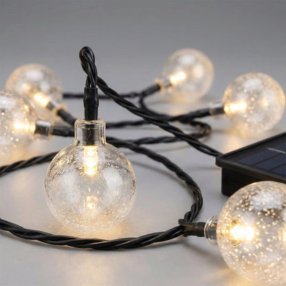 String of clear globe lights with solar panel on a neutral background