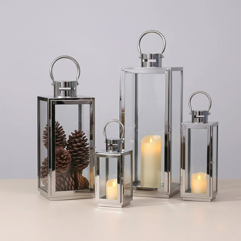 Set of four silver lanterns with candles on a light gray background