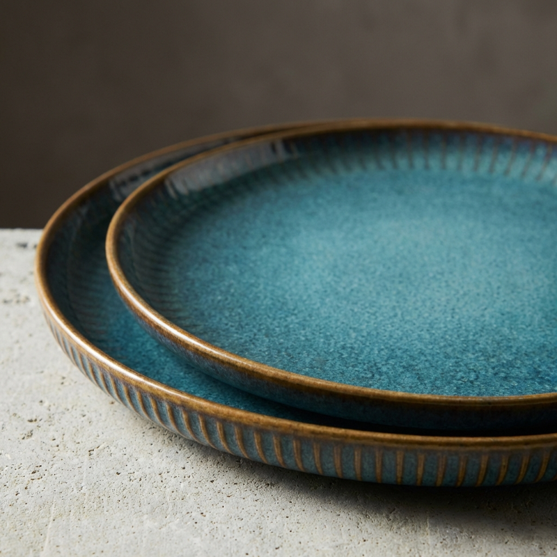 Two blue ceramic plates with brown rim on a gray surface