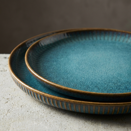 Two blue ceramic plates with brown rim on a gray surface