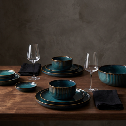 Set of blue ceramic dinnerware with black rims on a wooden table against a dark background