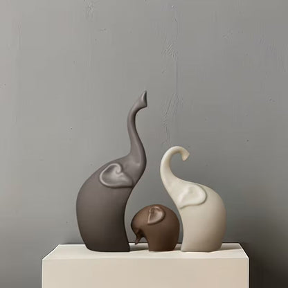 Three abstract ceramic elephant figurines on a white surface.
