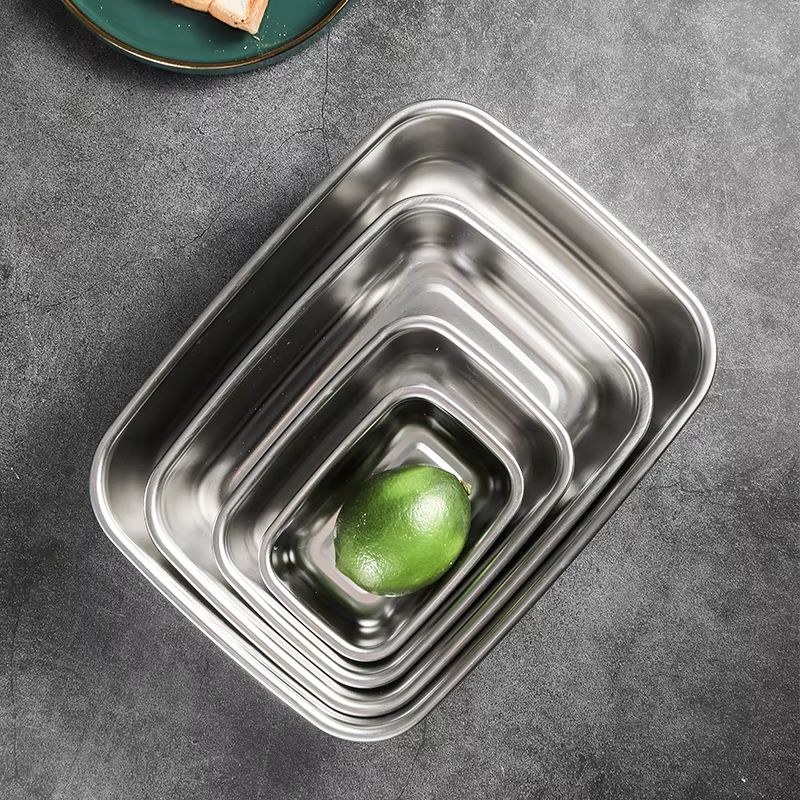 Five nested rectangular stainless steel containers, with a green lime in the smallest one.