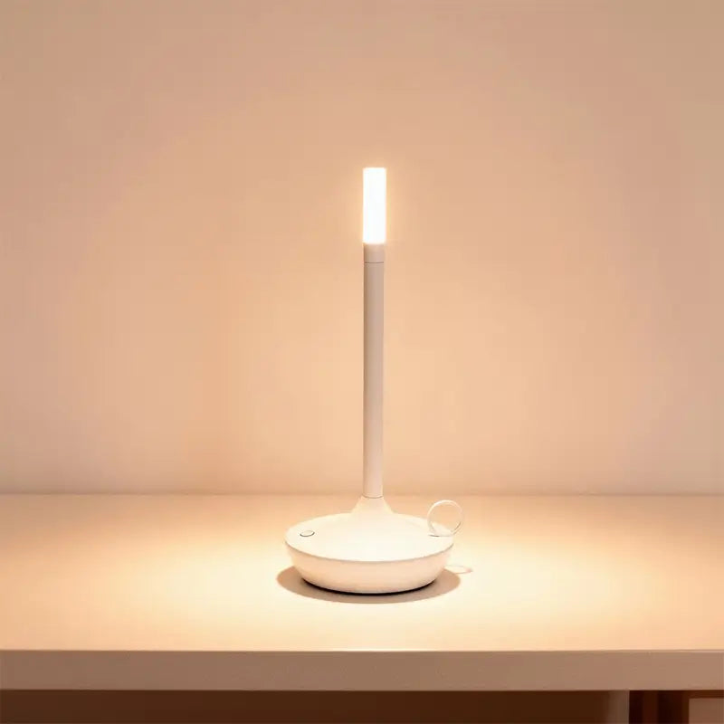 A slender white LED desk lamp is on, casting a warm light.