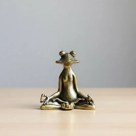 A small brass figurine of a frog sitting in a meditation pose.