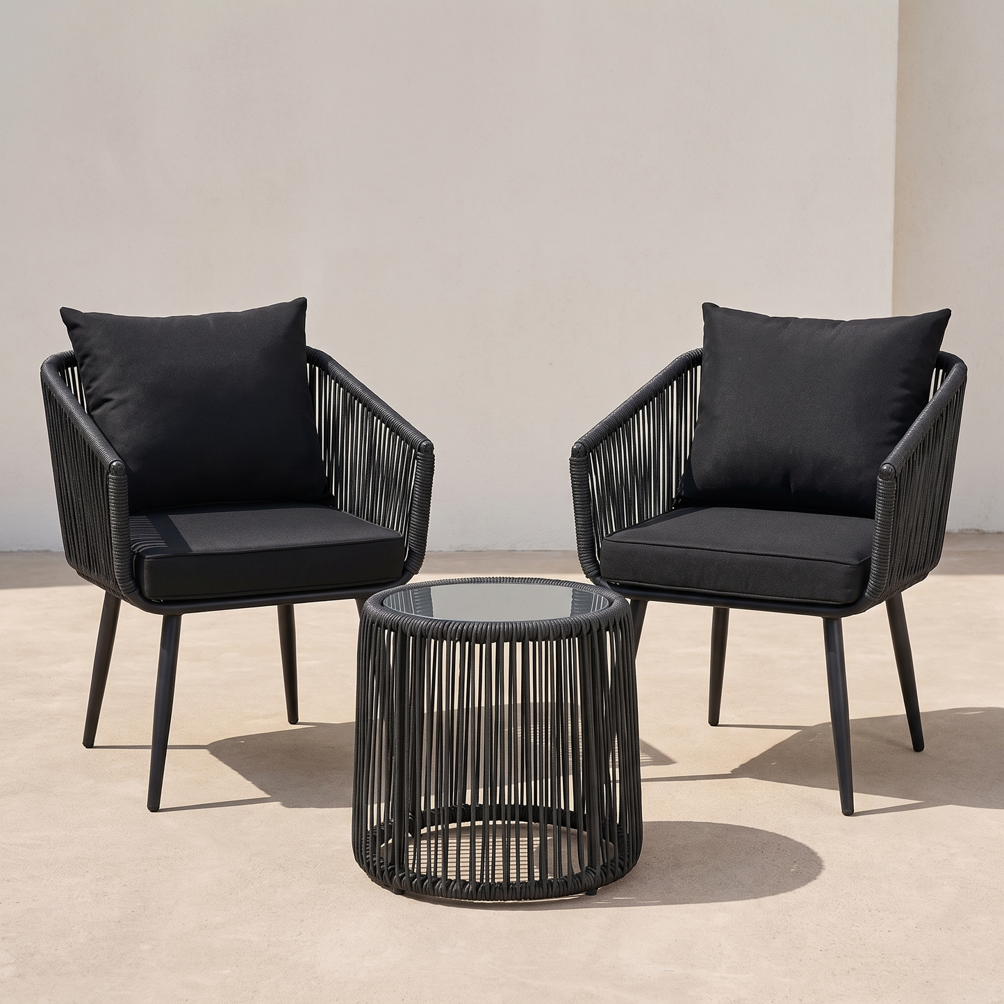Two black chairs with cushions and a matching table on a beige floor.
