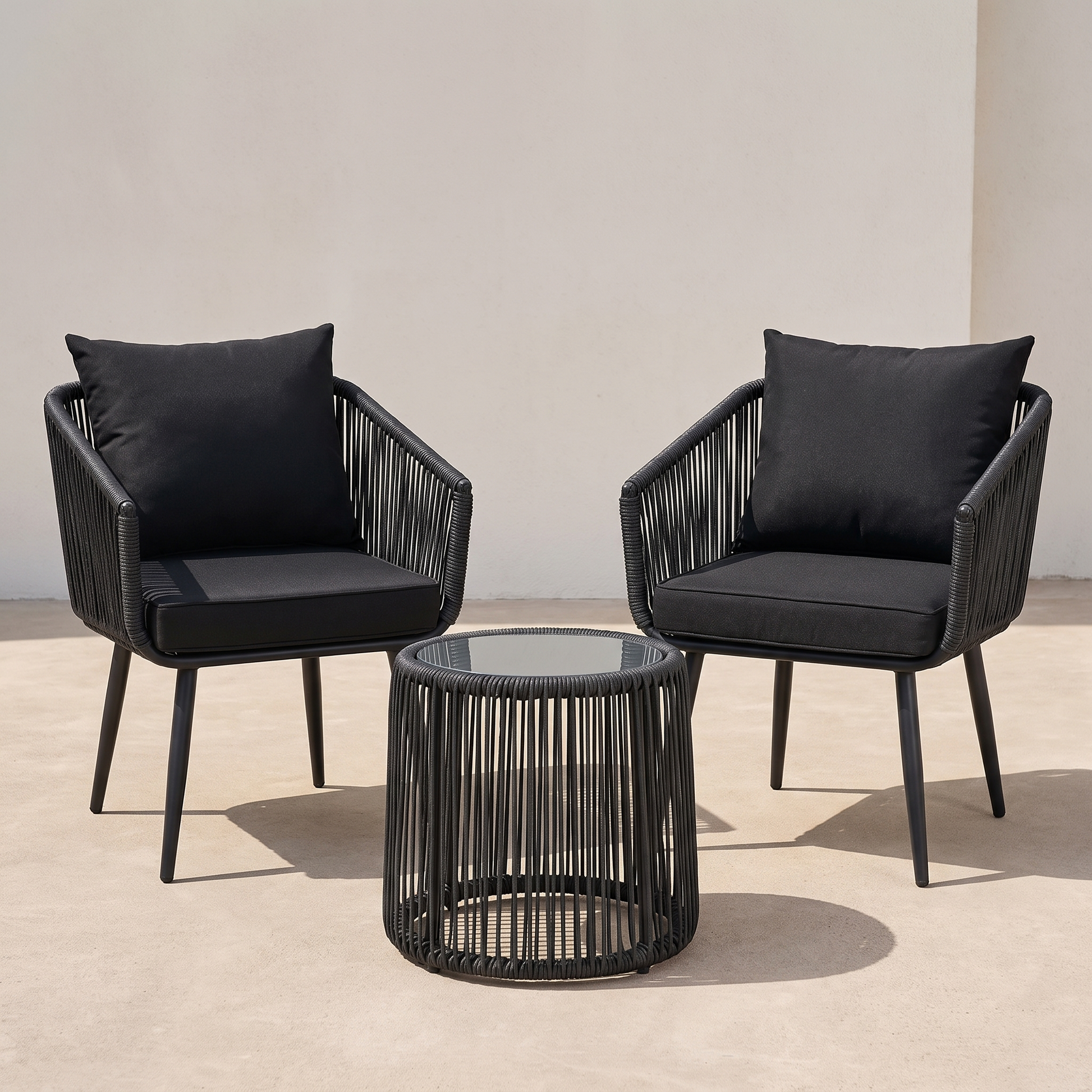 Two black chairs with cushions and a matching table on a beige floor.