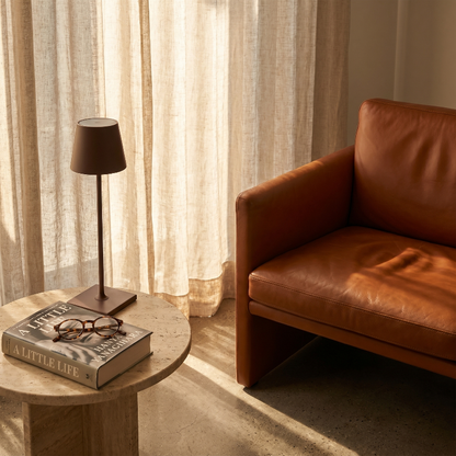 Allegra dimmable cordless table lamp on side table beside leather chair