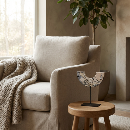 Arched Marble Sculptural Object on a wooden side table beside a linen armchair in a modern living room