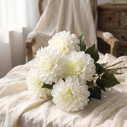 White dahlia bouquet resting on linen bedding in a bedroom