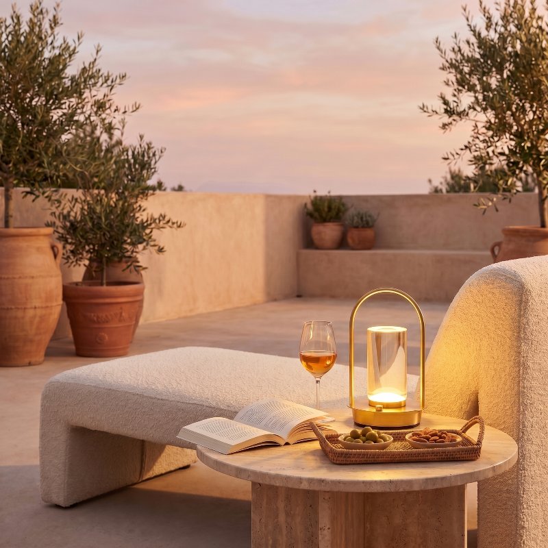 Aura portable crystal table lamp in gold on outdoor side table at sunset