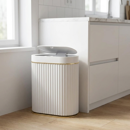 White automatic smart sensor trash can with gold trim styled in a modern bathroom