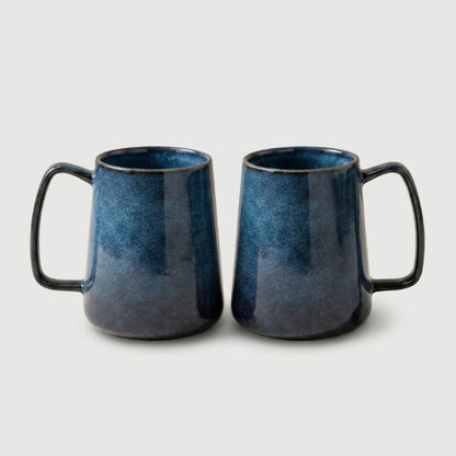 Set of two azure blue pottery mugs on white background