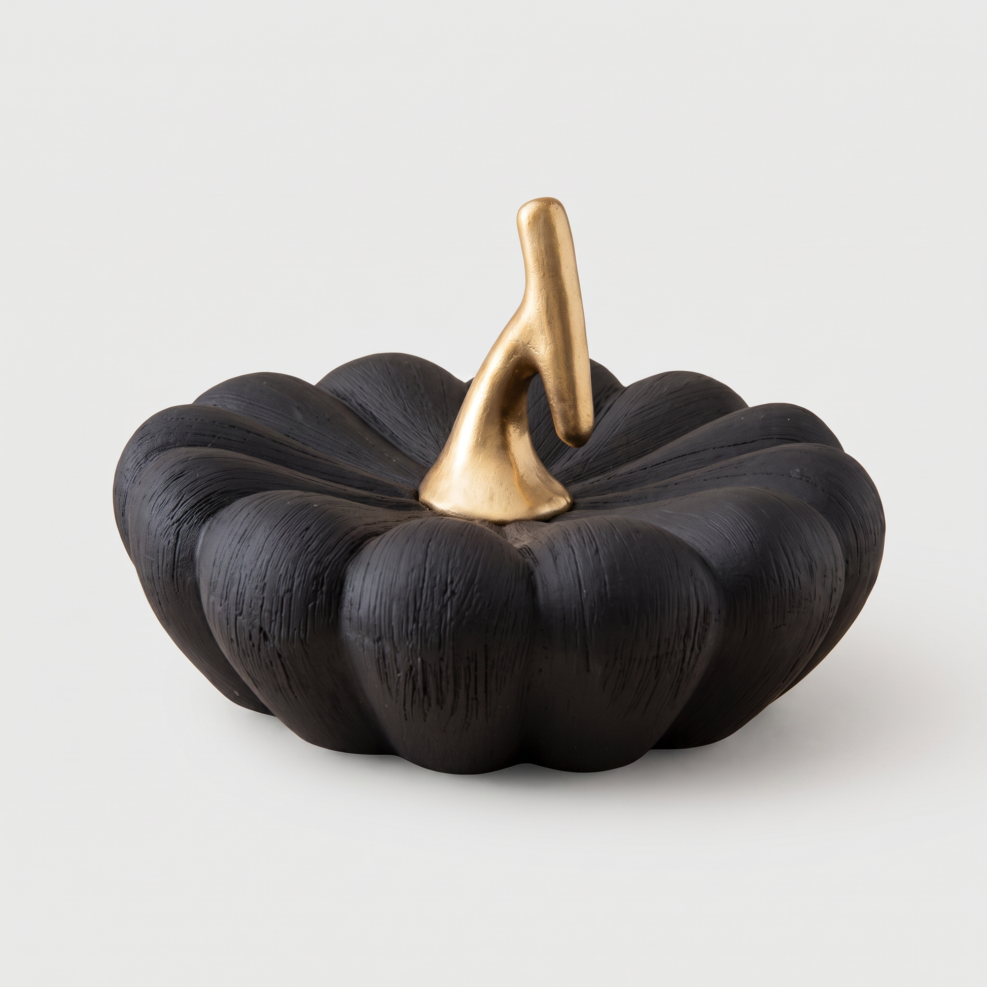 Large black decorative ceramic pumpkin with a gold stem on a clean off-white background