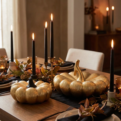 Black and gold decorative pumpkins on a dining table with candles for a fall table setting