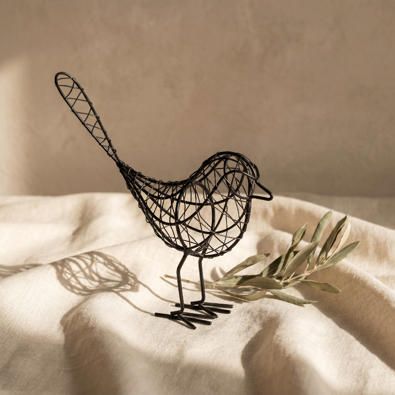 Iron bird sculpture on bed with tray and flower