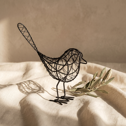 Iron bird sculpture on bed with tray and flower