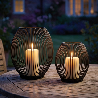 Black iron wire candleholders with lit candles on an outdoor table at dusk