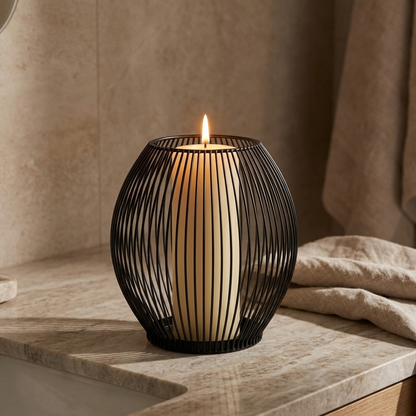 Black iron wire candleholder with a lit candle on a stone ledge