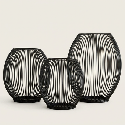 Set of three black iron wire candleholders in small, medium, and large sizes on a clean off-white background