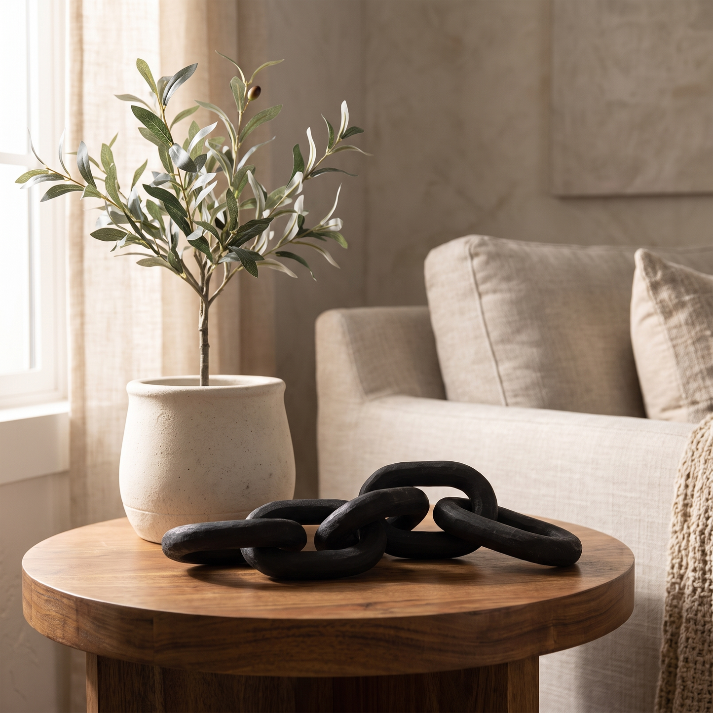Black wooden decorative chain arranged on a round wood side table beside a potted plant
