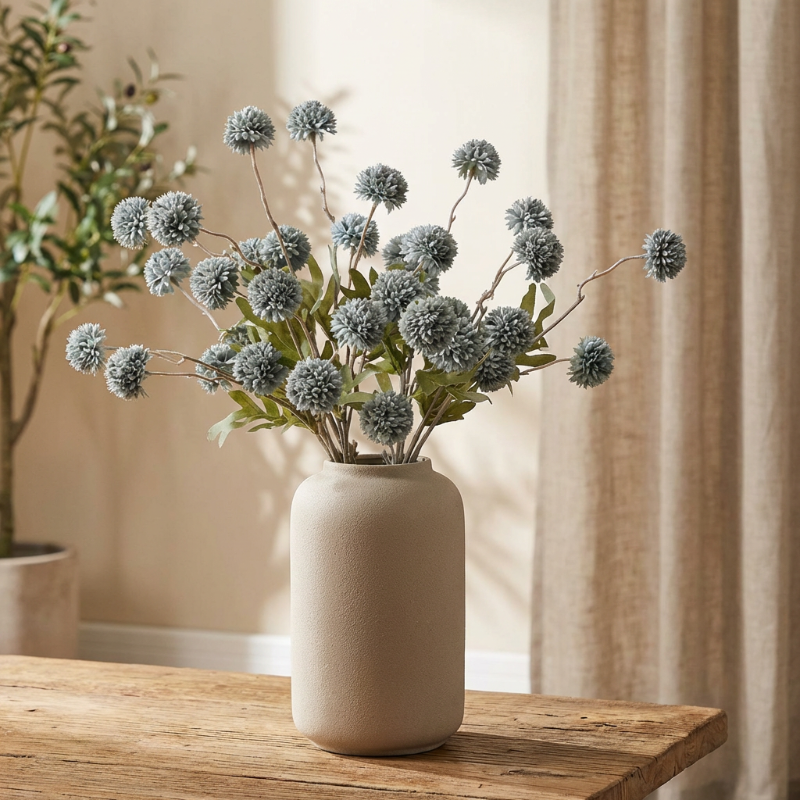 Blue faux dandelion stems in white vase on console table