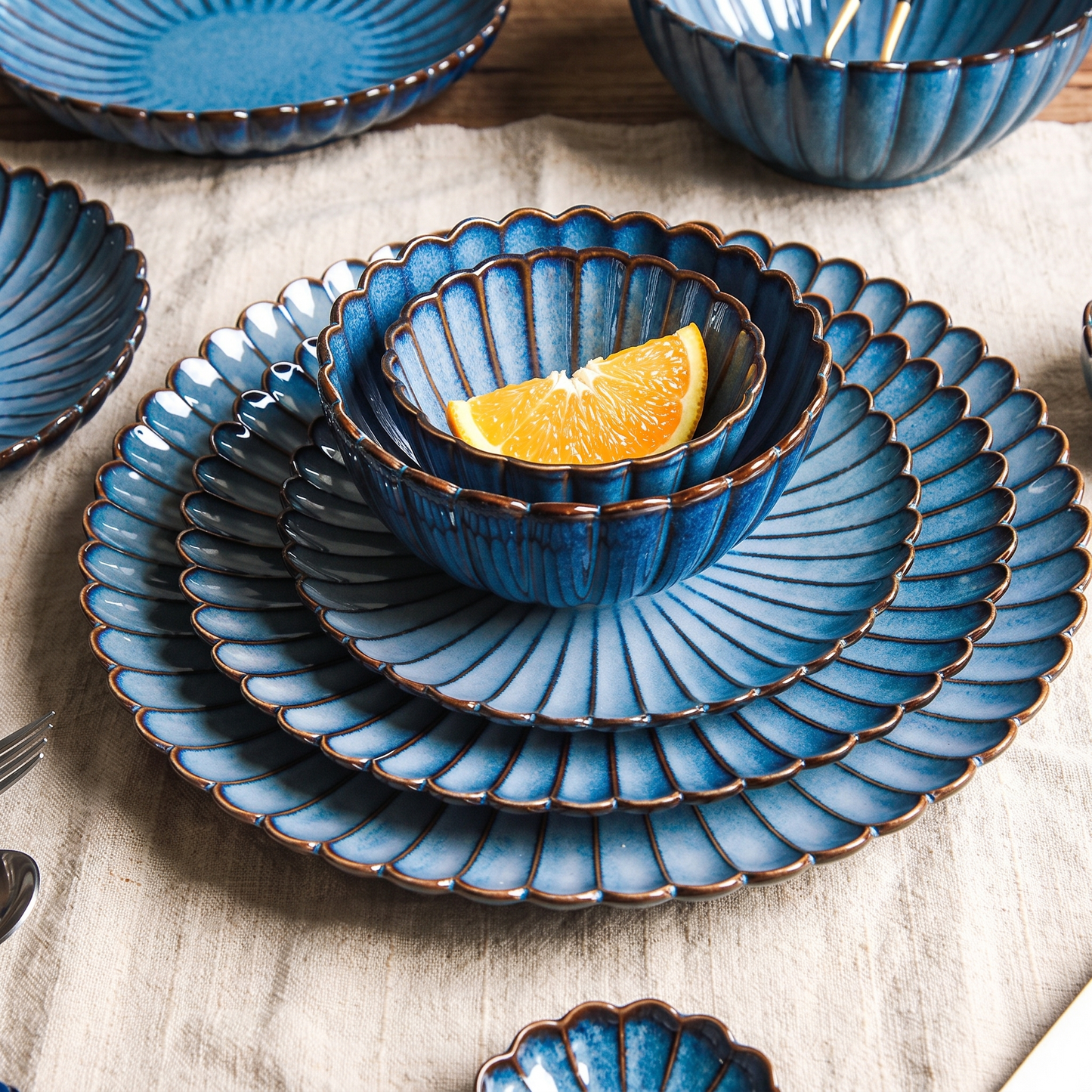 Stacked blue ribbed ceramic plates and bowls in moody lighting with an orange slice, Kiyo Home 22-piece set
