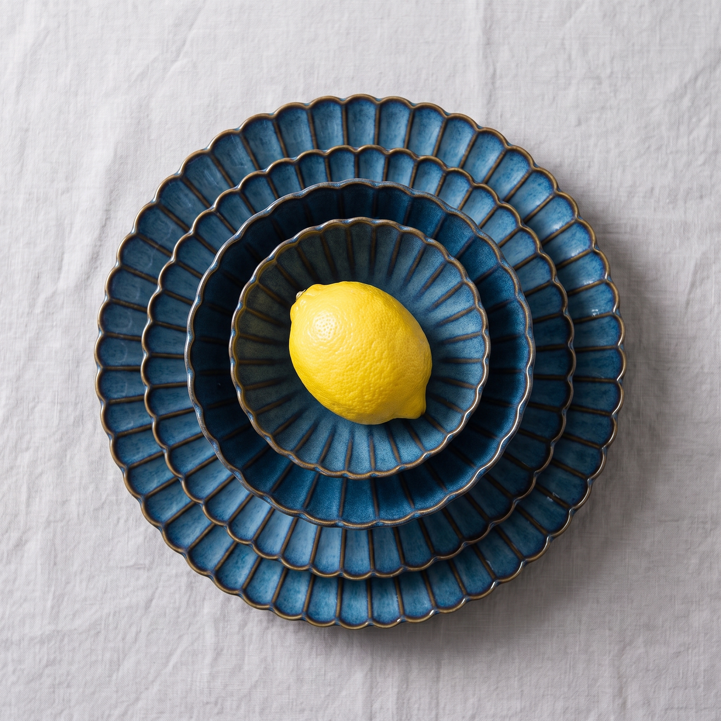 Overhead nested blue ribbed ceramic plates and bowls with a lemon, Kiyo Home 22-piece dinnerware set