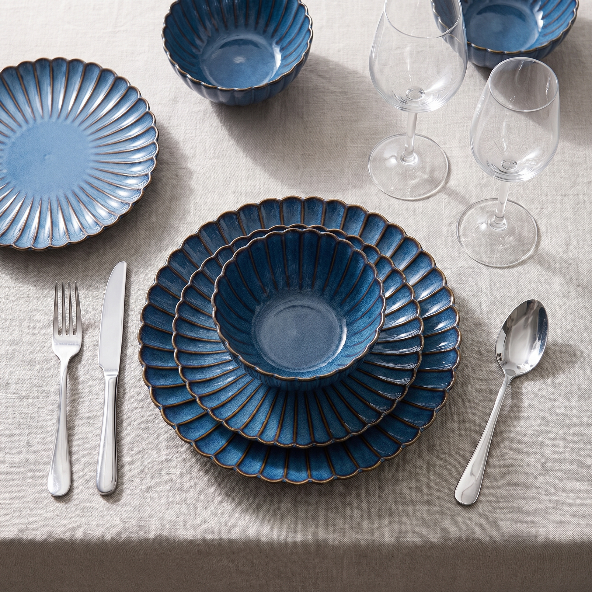 Overhead blue ribbed ceramic place setting with flatware and wine glasses, Kiyo Home 22-piece dinnerware set