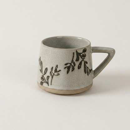 Botanical ceramic coffee mug with a hand-painted leaf botanical design on a clean off-white background