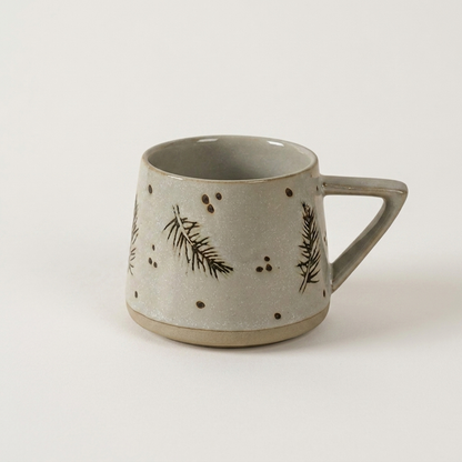 Botanical ceramic coffee mug with a hand-painted fern sprig design on a clean off-white background