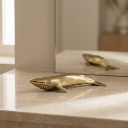 Brass blue whale figurine styled on stone ledge