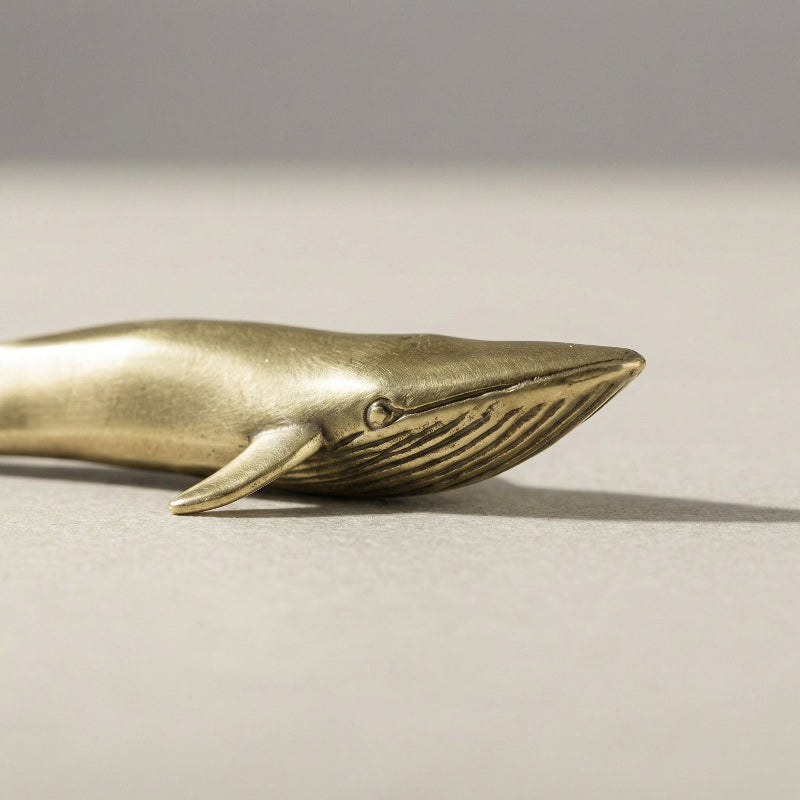 Close-up of brass blue whale figurine on white background