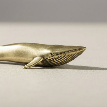 Close-up of brass blue whale figurine on white background