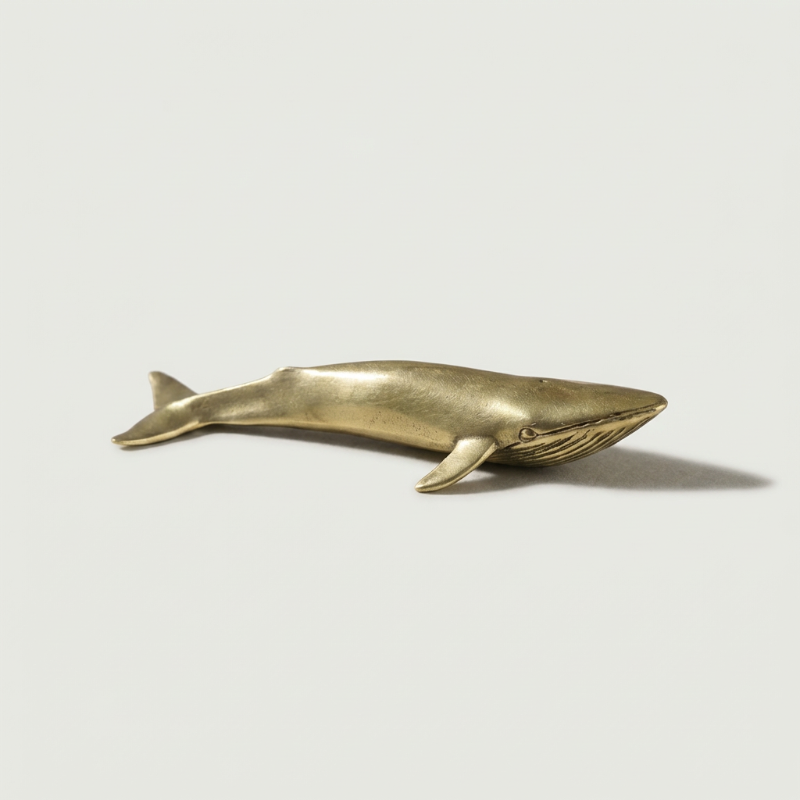 Brass blue whale figurine on white background