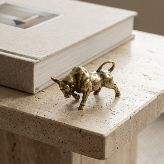 Bronze bull figurine on a stone surface with a book in the background