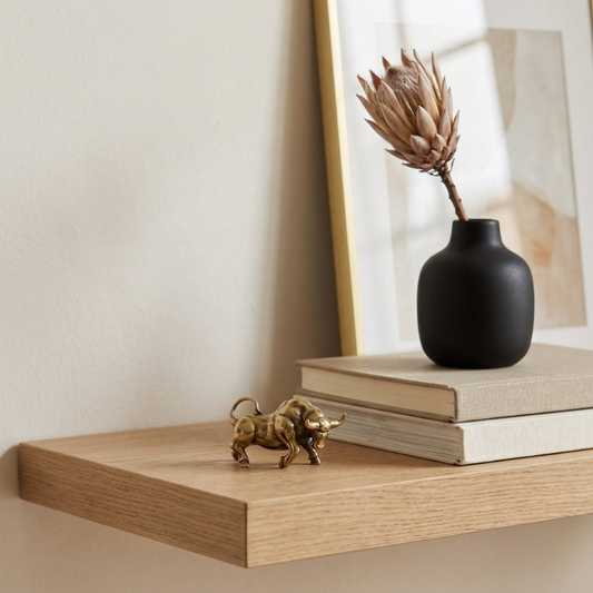 Decorative shelf with a black vase, books, and a gold bull figurine.