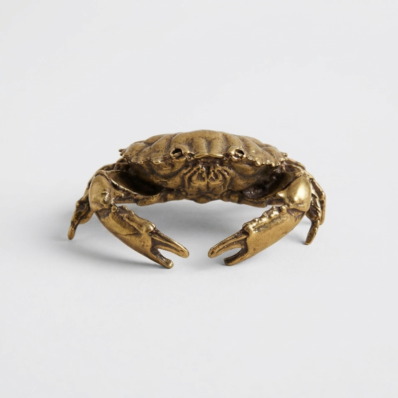 Bronze crab sculpture on a light gray background