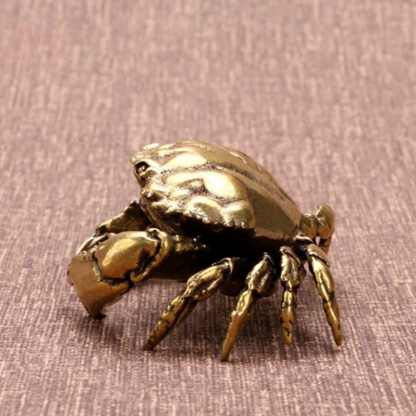Bronze crab figurine on a textured brown surface